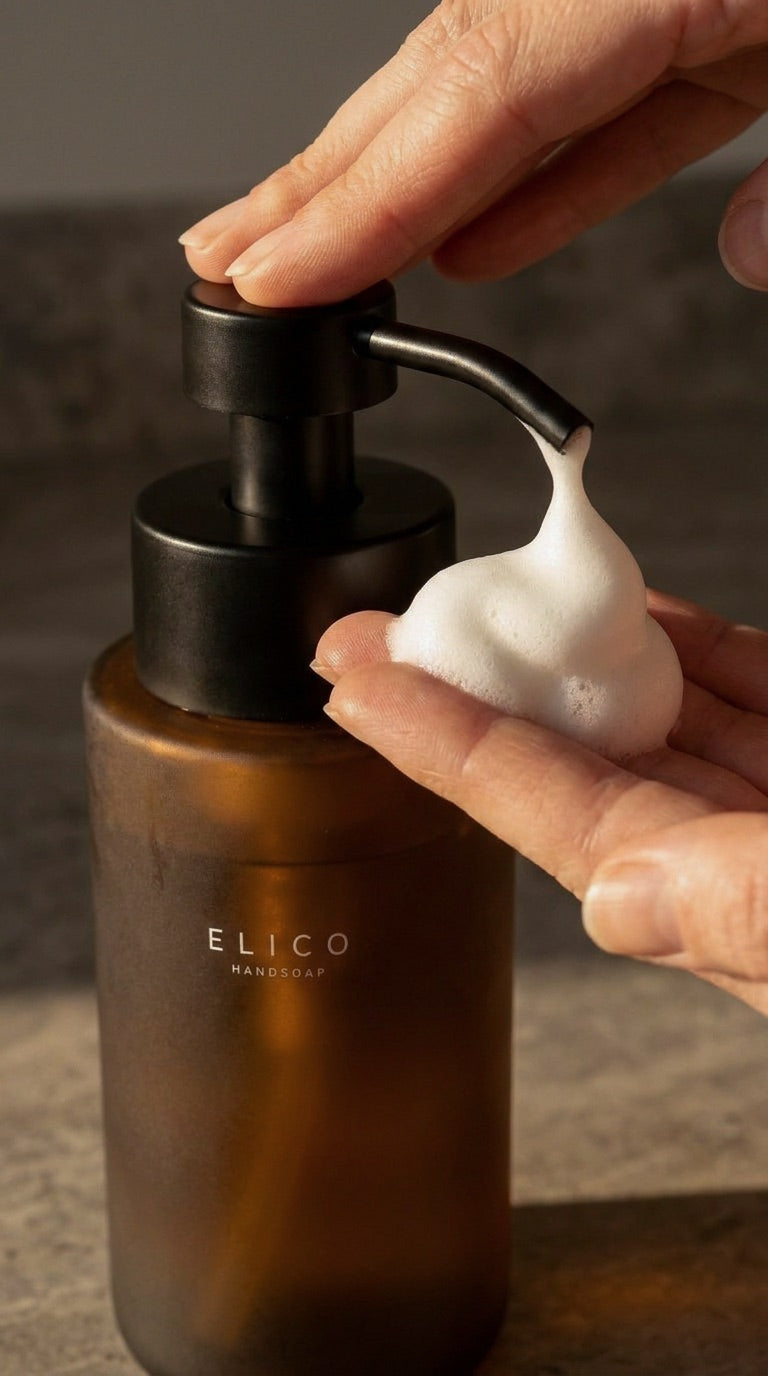 Close-up van een hand die schuim uit een dispenser van amberkleurig glas neemt