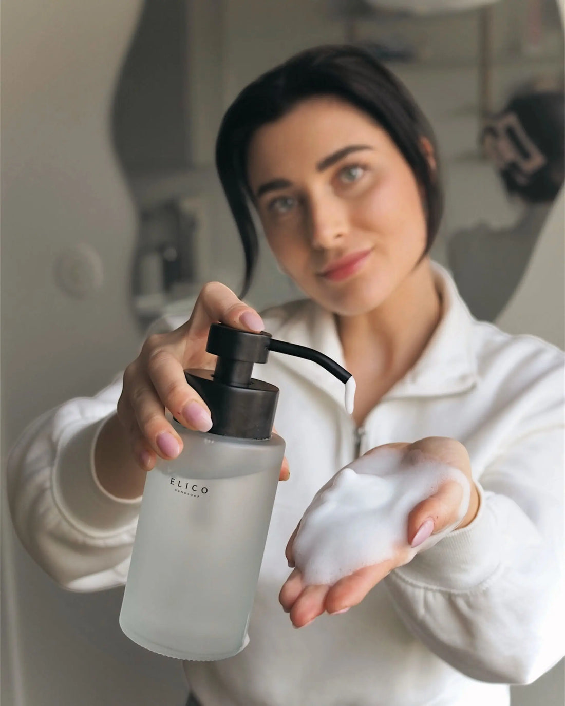 Vrouw met een matglazen dispenser en schuim in haar hand